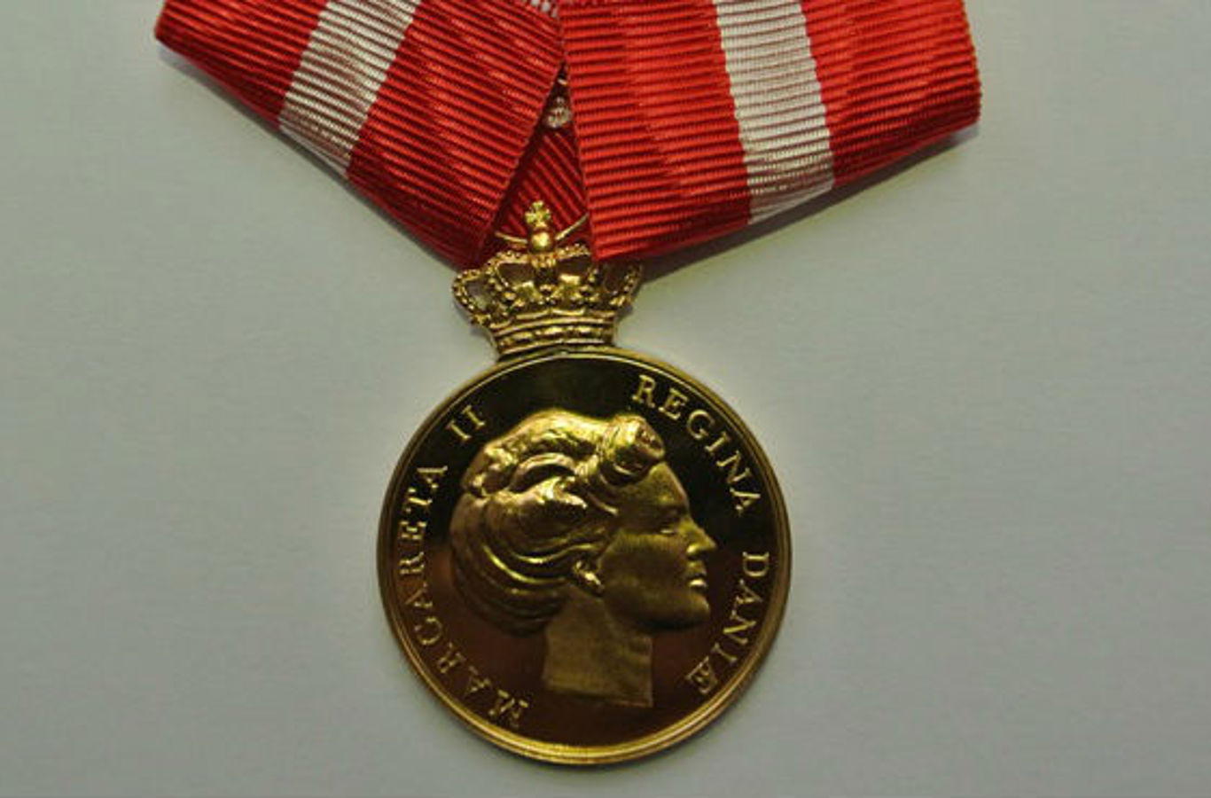 Den Kongelige Belønningsmedalje i guld med krone og inskription.