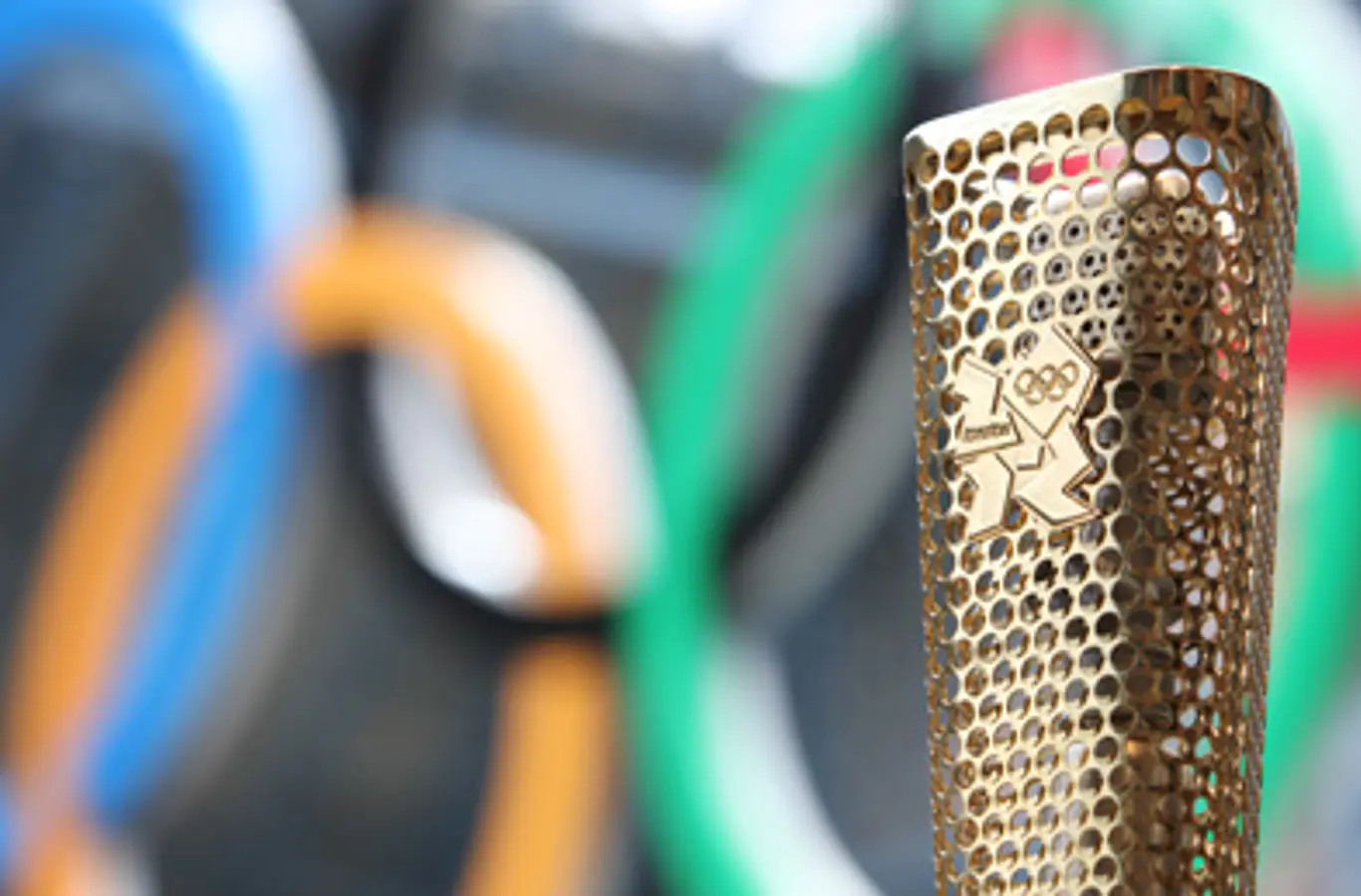 Den olympiske fakkelstav 2012 med de olympiske ringe i baggrunden.